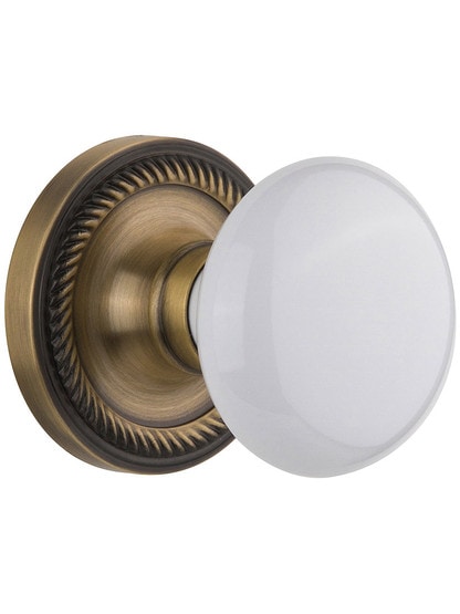 White Porcelain Doorknob Set with Rope Design Rosettes Single Dummy in Antique Brass.